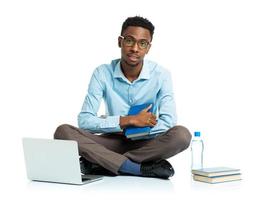 gelukkig Afrikaanse Amerikaans college leerling met laptop, boeken en fles van water zittend Aan wit foto