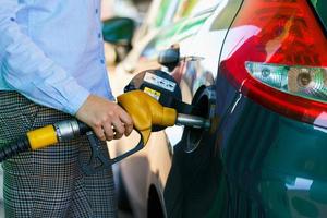 vrouw vult benzine in de auto Bij een gas- station foto