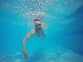 baard Mens met bril zwemmen onder water in de zwembad foto