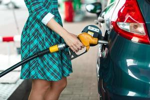 vrouw vult benzine in haar auto Bij een gas- station foto