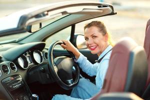 vrouw zittend in een converteerbaar auto - concept van buying een gebruikt auto of een verhuur auto foto