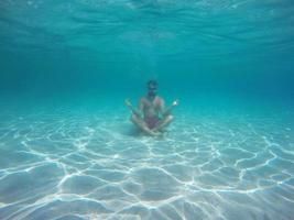 baard Mens met bril in de lotus positie mediteren onder water foto