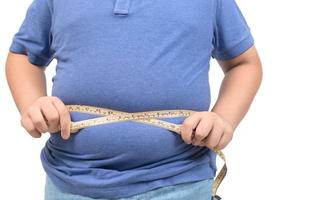zwaarlijvig dik jongen meten plakband van maag geïsoleerd Aan wit achtergrond, foto