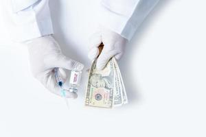 dokter hand- houdt injectiespuiten en vaccins en geld ons dollar geïsoleerd foto