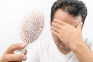 middelbare leeftijd Mens shows kam borstel met verlies haar- en benadrukt over zijn haar- verlies problemen foto