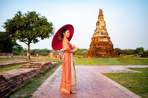 mooi Thais meisje in traditioneel jurk kostuum rood paraplu net zo Thais tempel waar is de openbaar plaats, Thais vrouw in traditioneel kostuum van Thailand. foto