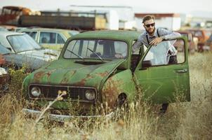 jong elegant knap Mens, vervelend overhemd en zonnebril, het rijden oud auto foto