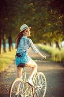 lief jong vrouw in een hoed rijden een fiets buitenshuis. actief mensen foto