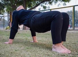 jong Indisch vrouw beoefenen yoga buitenshuis in een park. mooi meisje praktijk eenvoudig yoga houding. rust en kom tot rust, vrouw geluk. eenvoudig yoga poses buitenshuis foto