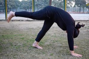 jong Indisch vrouw beoefenen yoga buitenshuis in een park. mooi meisje praktijk eenvoudig yoga houding. rust en kom tot rust, vrouw geluk. eenvoudig yoga poses buitenshuis foto