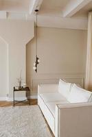 elegant Scandinavisch interieur van een knus leven kamer met een wit sofa en een koffie tafel en een lamp bovenstaand het foto