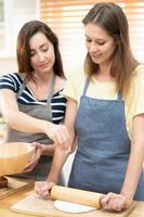 twee Kaukasisch Dames Koken pizza samen in de keuken. de concept van huisgemaakt voedsel en lgbt verhoudingen. familie en verscheidenheid concept. lgbt. foto