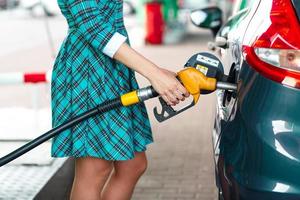 vrouw vult benzine in de auto Bij een gas- station foto