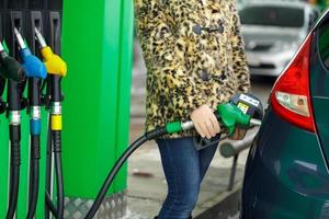 vrouw vult benzine in haar auto Bij een gas- station in winter foto