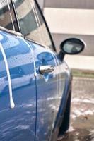 hand- wassen met zeep, roze schuim Aan de lichaam. auto het wassen met hoog druk water. foto