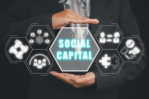 sociaal hoofdstad concept, persoon hand- Holding sociaal hoofdstad icoon Aan virtueel scherm. foto