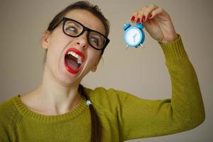 weinig blauw alarm klok in de handen van een emotioneel jong vrouw foto