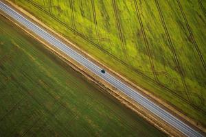 visie van de hoogte Aan de auto het rijden langs een landelijk weg tussen twee velden foto