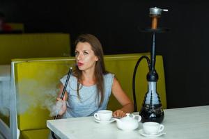 mooi vrouw roken een hookah en drinken thee in een cafe foto