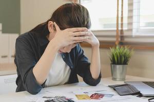 financieel verschuldigd Aziatisch vrouw zittend Hoes gezicht met handen, benadrukt door berekenen kosten van factuur of rekening, hebben Nee geld naar betalen, hypotheek of lening. schuld, faillissement of failliet concept. foto