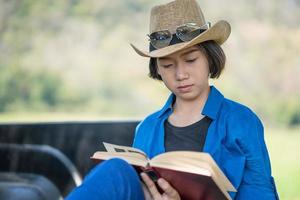 vrouw slijtage hoed en lezing de boek Aan oppakken vrachtauto foto