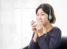 jong Aziatisch vrouw kort haar- luisteren muziek- in leven kamer foto