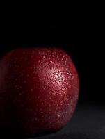 rood sappig appel met druppels van water Aan een zwart achtergrond. isoleren. kopiëren ruimte. dichtbij omhoog foto