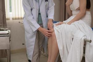 vrouw volwassen traumatoloog dokter onderzoeken geduldig knie Bij ziekenhuis medisch kantoor foto