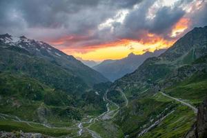 een panorama van een voorbij gaan aan weg gedurende zonsondergang, de lucht is oranje foto