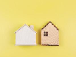 vlak leggen van twee houten model- huizen Aan geel achtergrond. foto