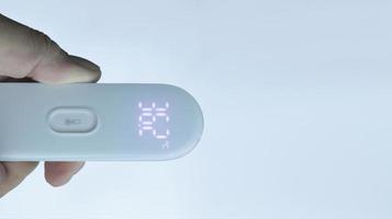 een hand- Holding digitaal thermometer tonen normaal temperatuur met geïsoleerd Aan wit. foto