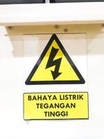 Gevaar hoog Spanning teken met tekst geïsoleerd geel insigne in Indonesisch bahaya listrik tegangaan tinggi foto