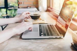 bijgesneden schot visie van zakenvrouw gebruik makend van haar laptop en nemen een koffie breken in kantoor. foto