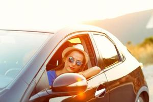 glimlachen vrouw het rijden een auto Bij zonsondergang foto