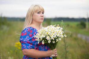 mooi plus grootte vrouw met wit haar- in een zomer jurk poseren buitenshuis met madeliefjes. mollig meisje in een weide met bloemen. foto