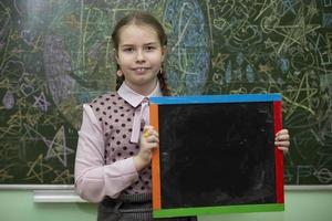 schoolmeisje van midden- school- leeftijd met een leeg leisteen bord. foto