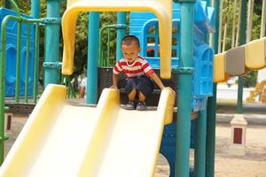 jongen spelen in de speelplaats in de park foto