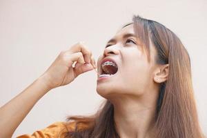 Aziatisch vrouw plukken voedsel kladjes van haar tanden foto