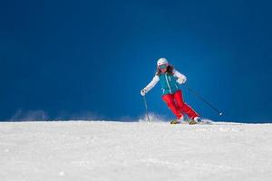 vrouwelijke skiër skiën bergafwaarts tijdens zonnige dag foto