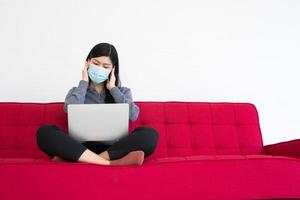 vermoeide vrouw met een gezichtsmasker, hoofdpijn en migraine, het lijden van het kantoorsyndroom na urenlang werken op de computer. office-syndroom en zorgconcept. foto