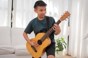 portret van een Aziatisch gelukkig glimlachen jongen hebben pret spelen gitaar muziek- concept, kinderen muziek- school. rots concert, muziek- voor kinderen en peuters concept foto