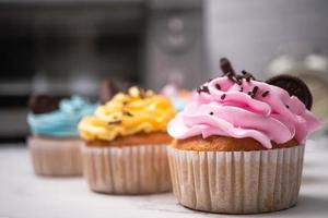 heerlijke zelfgemaakte cupcakes met kleurrijke slagroom en topping met snoep en chocoladekoekjes. zelfgemaakte herfstvakantie dessert foto