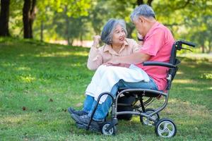 senior paar in de park en vrouw nemen zorg van een man in een rolstoel een geduldig met verlamming, met zijn vrouw geruststellend en bemoedigend elk ander. pensioen Gezondheid verzekering concept. foto