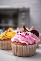 heerlijke zelfgemaakte cupcakes met kleurrijke slagroom en topping met snoep en chocoladekoekjes. zelfgemaakte herfstvakantie dessert foto