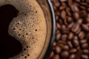 de top visie van een koffie kop en groep van zwart koffie bonen is de achtergrond. sterk zwart espresso, gronden van koffie achtergrond, structuur foto