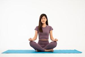 Aziatisch sportief en gezond jong vrouw aan het doen yoga praktijk en meditatie Aan yoga stootkussens geïsoleerd Aan wit achtergrond. concept van gezond leven foto