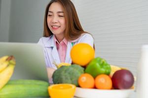 portret van Aziatische glimlachende vrouwelijke voedingsdeskundige die op laptopcomputer typt voor een uitgebalanceerd corrigerend dieetplan voor advies aan patiënten of gewichtsverlies. concept van gezonde levensstijl, gezonde voeding, dieet foto