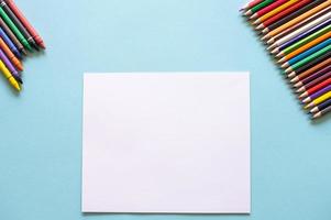een reeks van helder schrijfbehoeften items Aan een blauw achtergrond. gekleurde potloden en wit papier foto