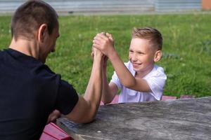 een schattig kind tests de sterkte van zijn handen met zijn pa. gewichtheffen foto