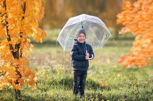 een jongen staat onder een paraplu gedurende de regen foto